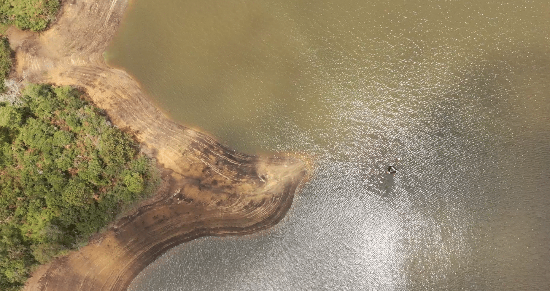 Aerial view of nutrient and sediment runoff entering a lake from the catchment shoreline with LG Sonic MPC-Buoy water quality monitoring device deployed on the water